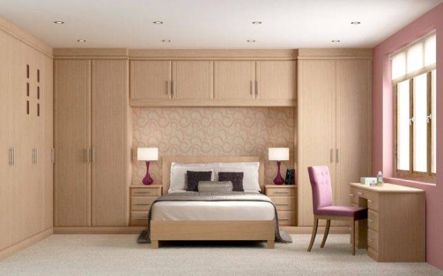 A bedroom with traditional cabinets, featuring ornamentation and wooden finishes.